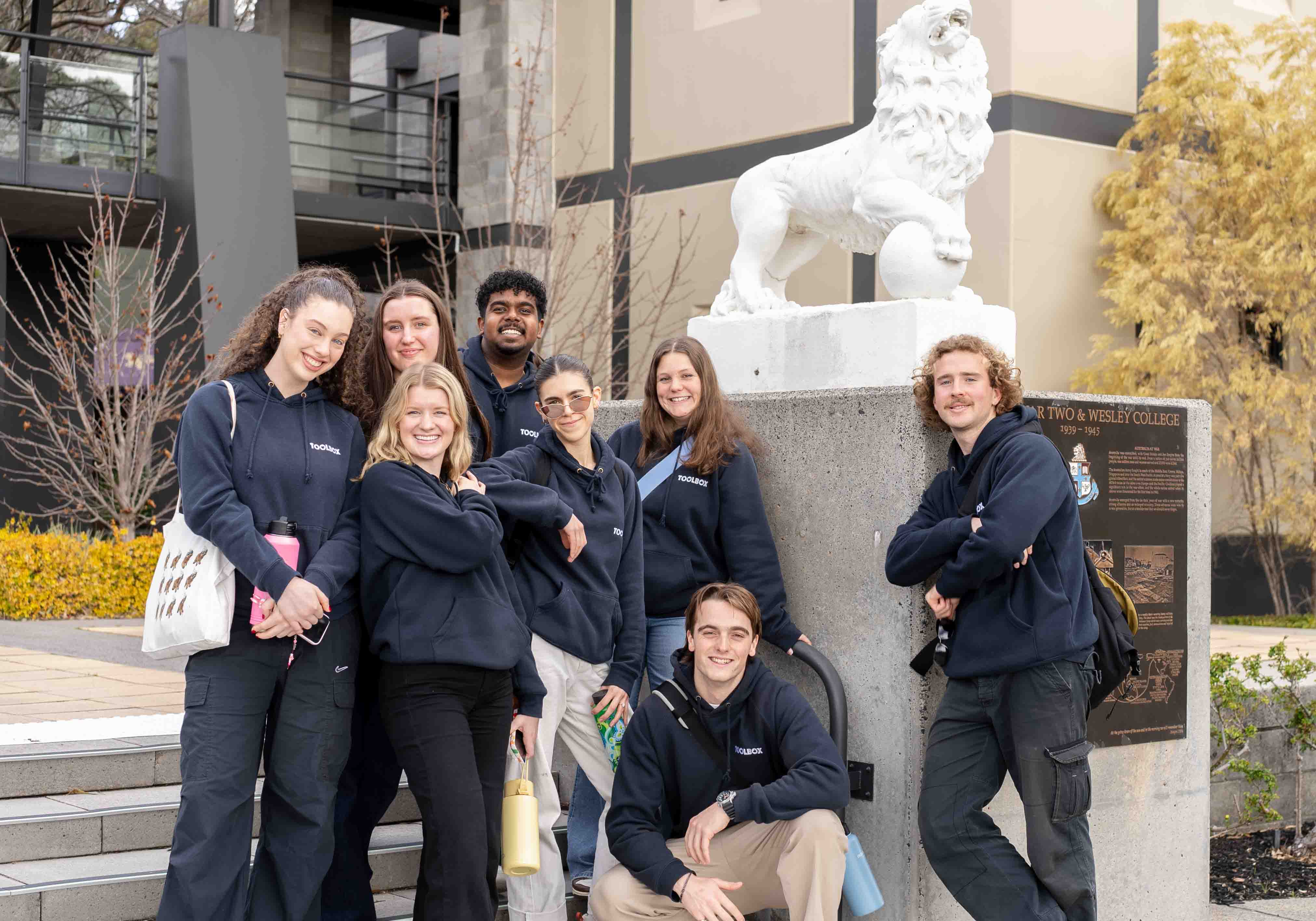 A group of Toolbox facilitators in Toolbox hoodies smiling together on campus
